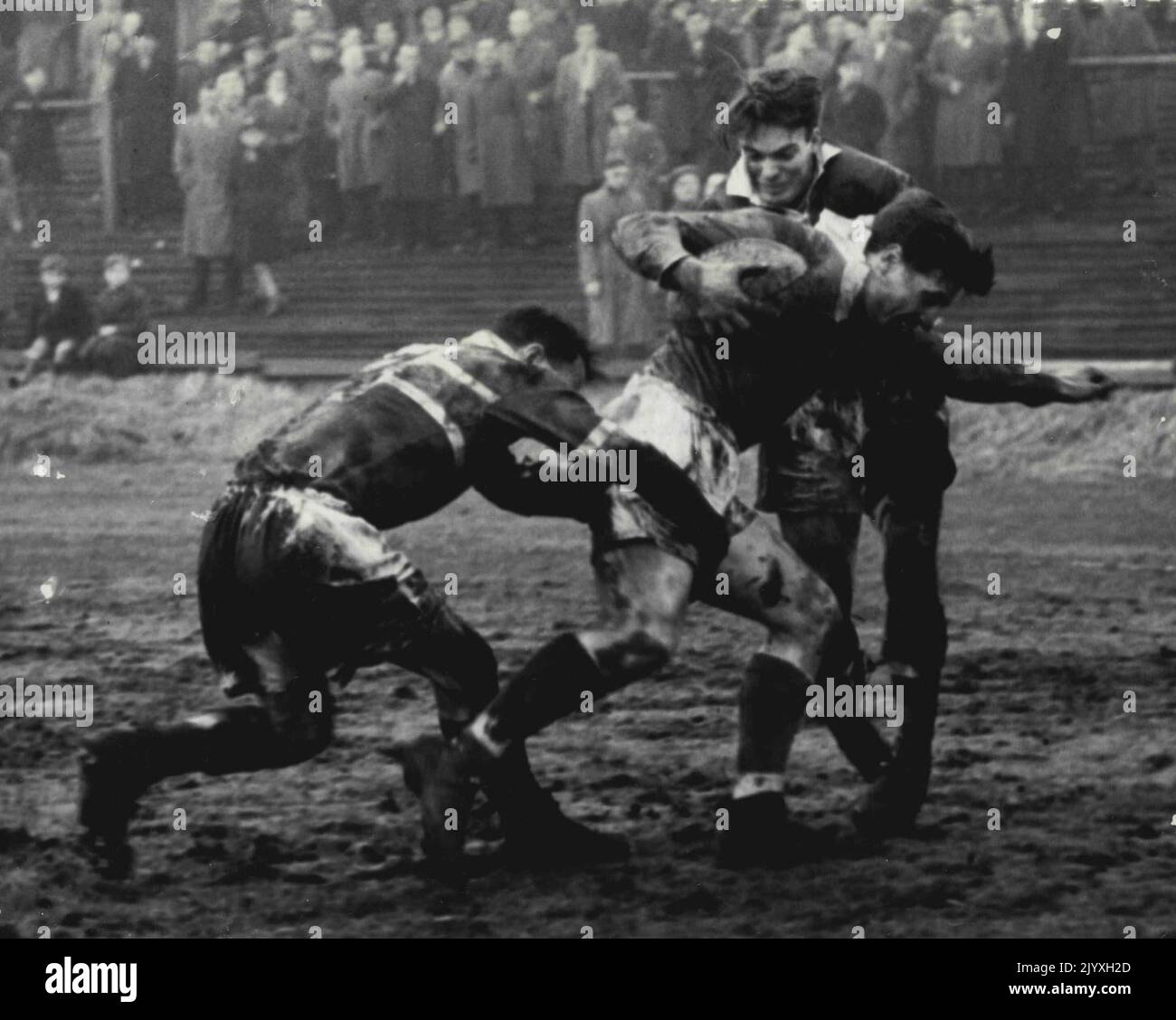 Swinton v Rochdale - Norburn of Swinton smiles as he tries to batter his way through a double tackle by. Harris and and Lord of Rochdale Hornets at Station Road, Ground, Swinton, today. February 27, 1954. Stock Photo