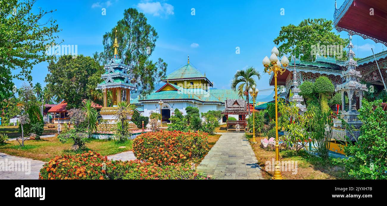 The beautiful blooming tropic garden with ornate shrines and viharns of Wat Chong Kham Temple, Mae Hong Son, Thailand Stock Photo