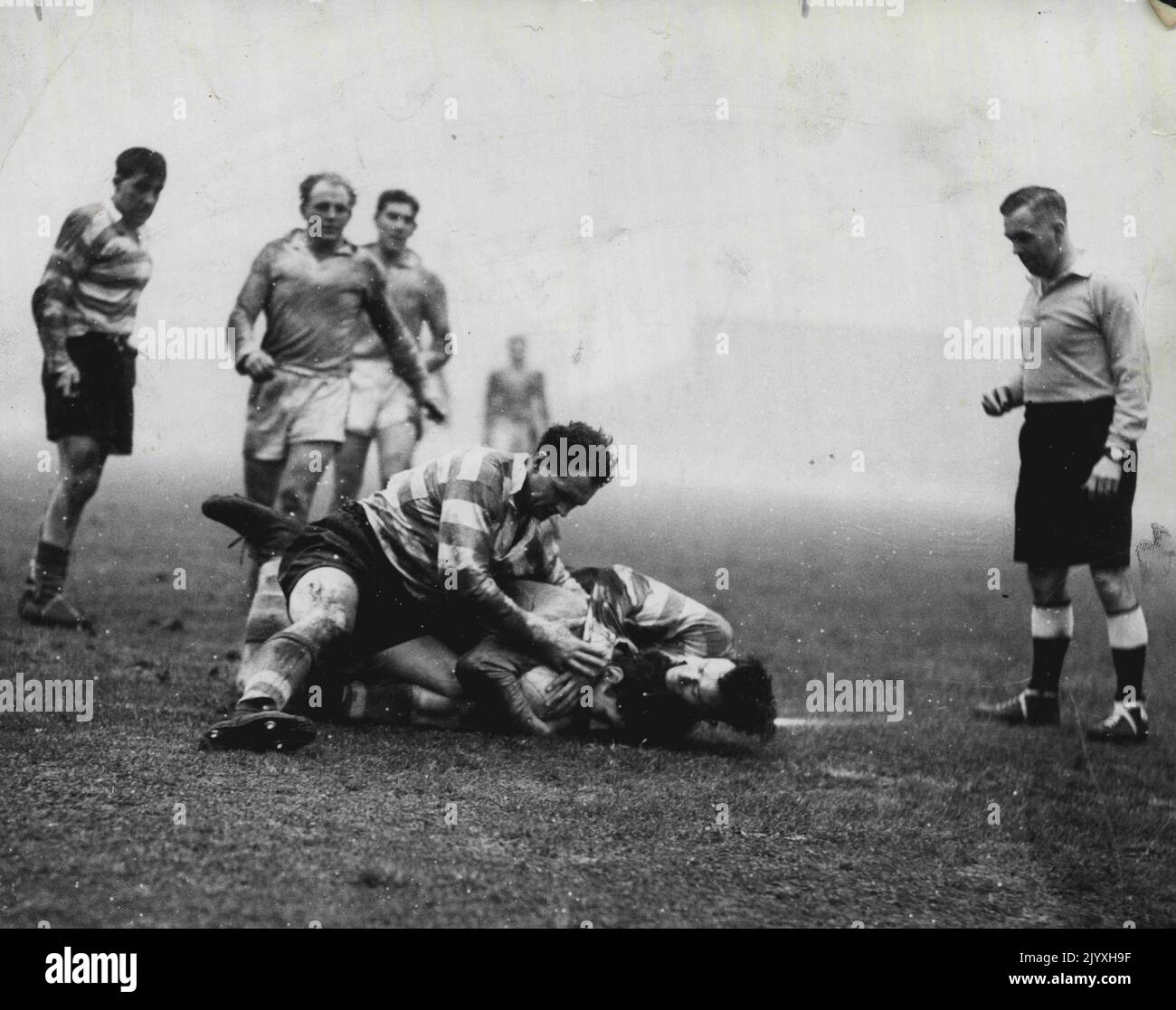 St. Helens v Oldham. Referee Charlie Appleton watches as Keith and Little, Oldham forwards, bring down Karalius, Saints forward. Crash. St. Helens forward Karalius gets no quarter from Oldham forwards Keith and Little in a recent Rugby League match in England. But Karalius made sure he kept possession of the ball. December 24, 1955. Stock Photo