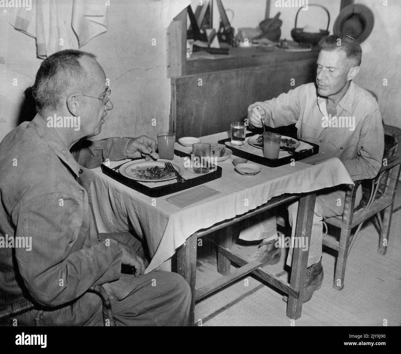 Complete Cleanup - Marine Lieut. Gen. Holland M. Smith (left) Fifth Amphibious Cors commanding general, and Admiral Raymond A. Spruance, USN, commander of the Fifth Fleet, cleanup their luncheon plates at 'chew' in a Japanese home at Charan Kanca, while the cleaning up operations on Saipan were in progress. The Monday meal consisted of canned corned beef, captured from the Japs, and canned American grape fruit juice. The luncheon trays and plates were found in the house. July 13, 1944. (Photo by Officials U.S. Marine Corps Photograph). Stock Photo