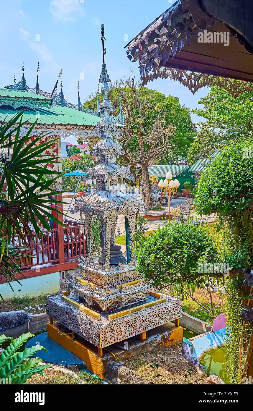 The carved lace-like silver mondop shrine, surrounded with lush greenery of garden of Wat Chong Kham Temple, Mae Hong Son, Thailand Stock Photo