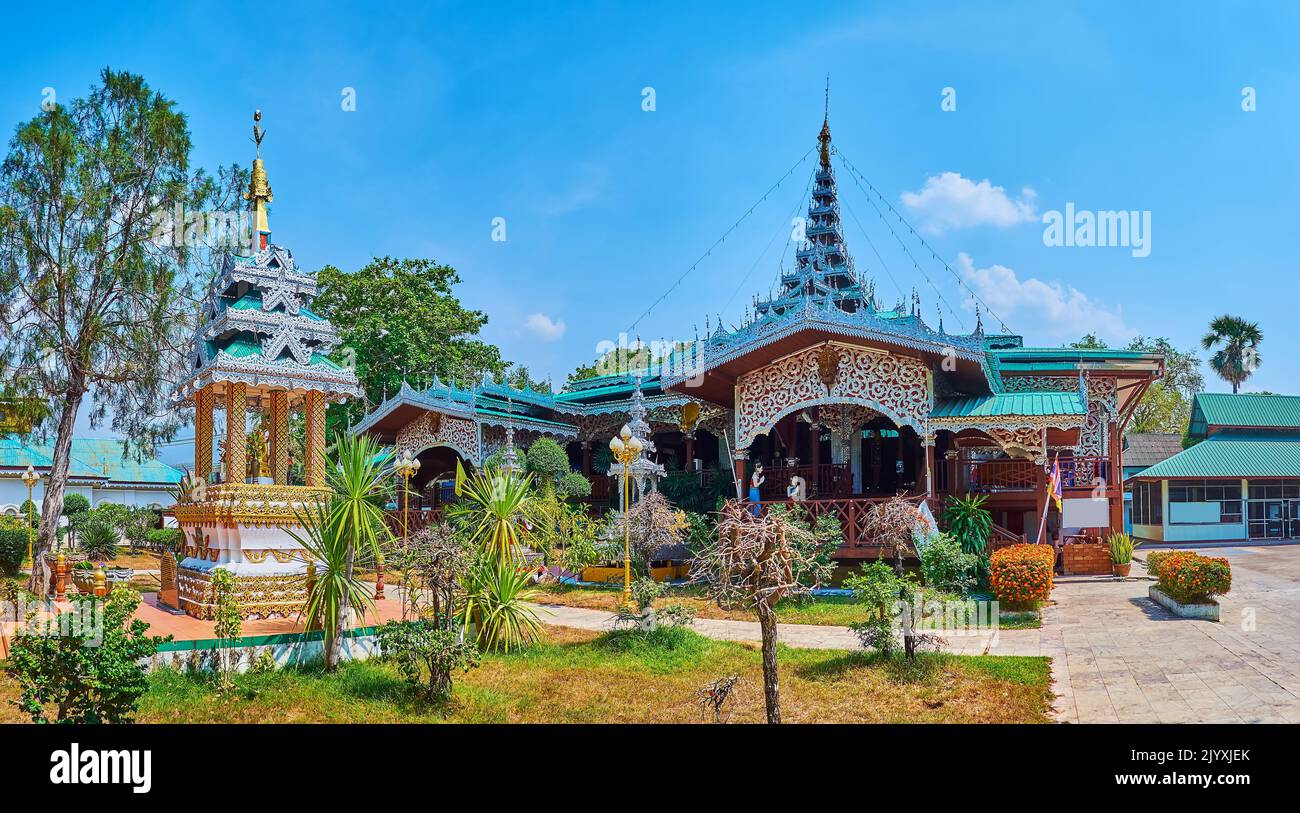 Panorama of the green garden, ornate wooden Viharn and small shrine of the Wat Chong Kham Temple in Mae Hong Son, Thailand Stock Photo