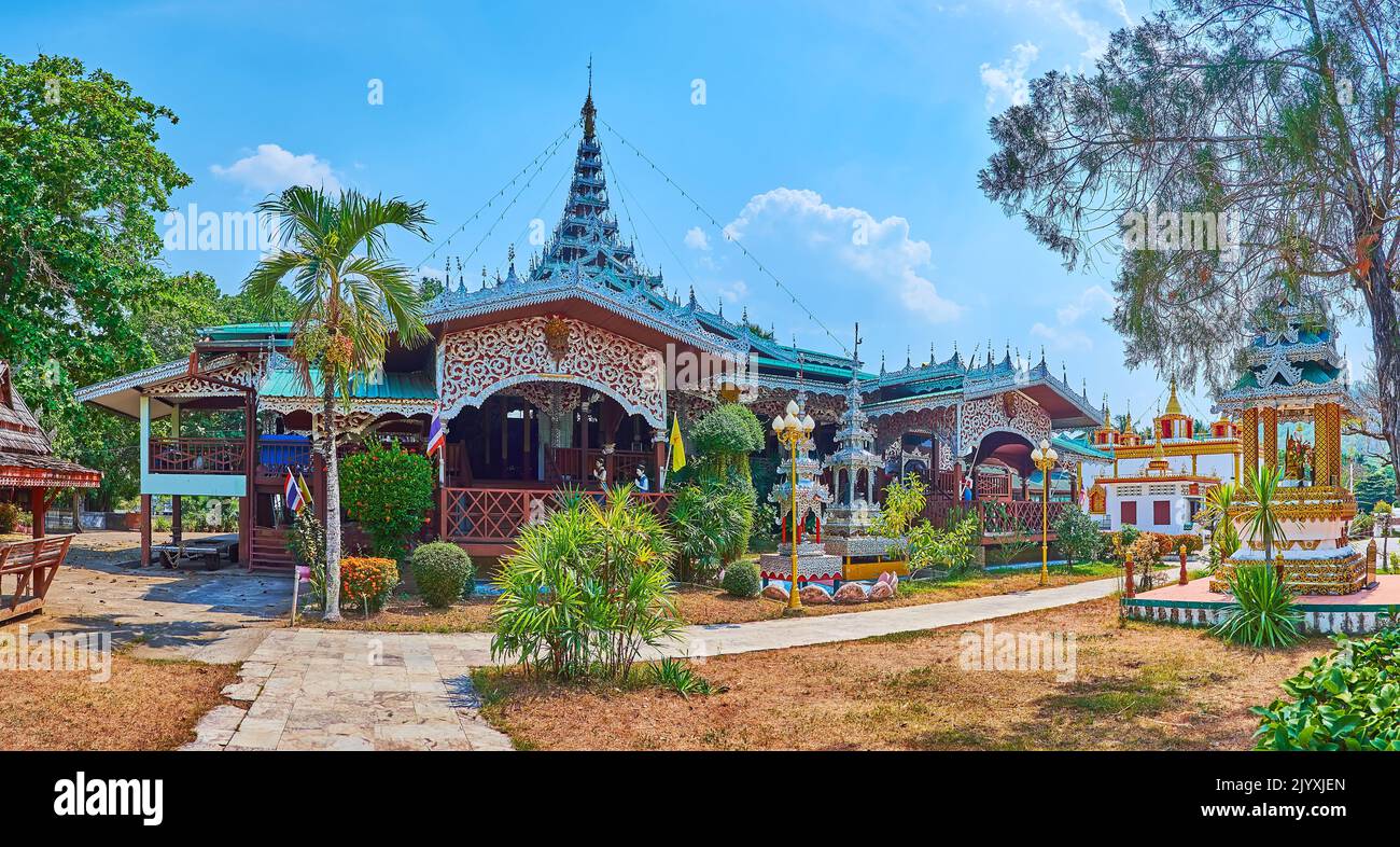 Panorama of Wat Chong Kham Temple with carved Viharn, topped with complex multi-tired roof and surrounded with tropical garden, Mae Hong Son, Thailand Stock Photo