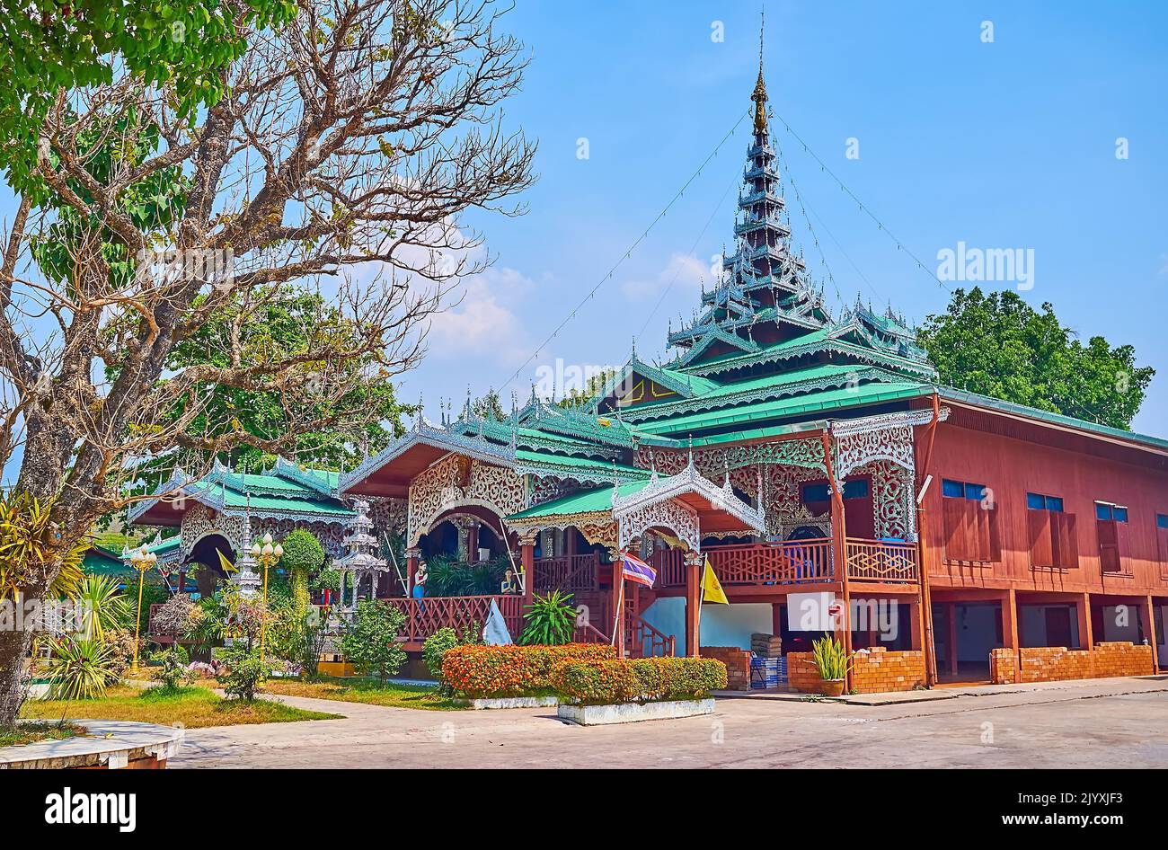 Exterior of carved wooden Viharn of Wat Chong Kham Temple, decorated with carved silver details of porch and tall pyathat (multi-tired) roof, Mae Hong Stock Photo