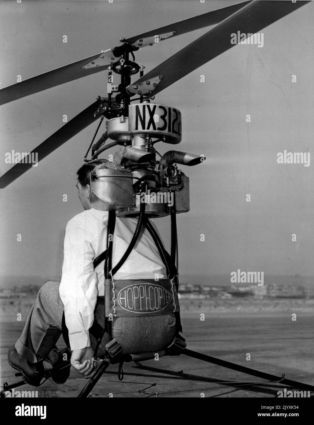 Air Motorcycle -- A rear view of the 'Hoppicopter' showing the left hand of the inventor, Horace Pentecost on the gas throttle. The pilot is strapped in just as in convention all planes. July 29, 1946. (Photo by Wide World Photos). Stock Photo