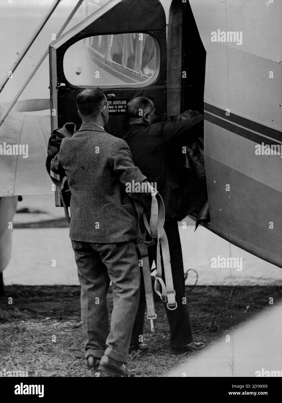 Qantas officials carrying parachutes to the machine in which ***** tests were made. November 23, 1934. Stock Photo