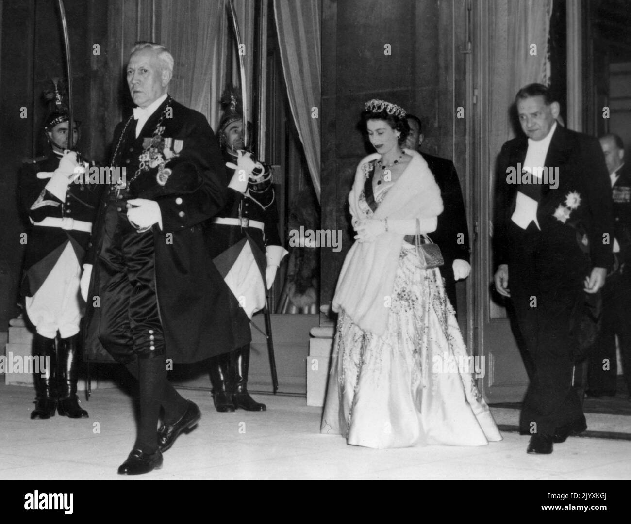 File photo dated 9/4/1957 of Queen Elizabeth II wearing a Norman Hartnell gown as she is escorted by her host, French President Rene Coty (right) as she leaves the Elysee Palace, Paris, to attend the gala performance at the Opera. Elizabeth II was famed for her love of block colours and matching hats and her fashion became a legendary part of her role as monarch. The Queen was once described as 'power dressing in extremis' for using vibrant shades to make herself stand out from the crowd while her hats allowed her to be easily spotted but were small enough so her face was visible. Issue date:  Stock Photo