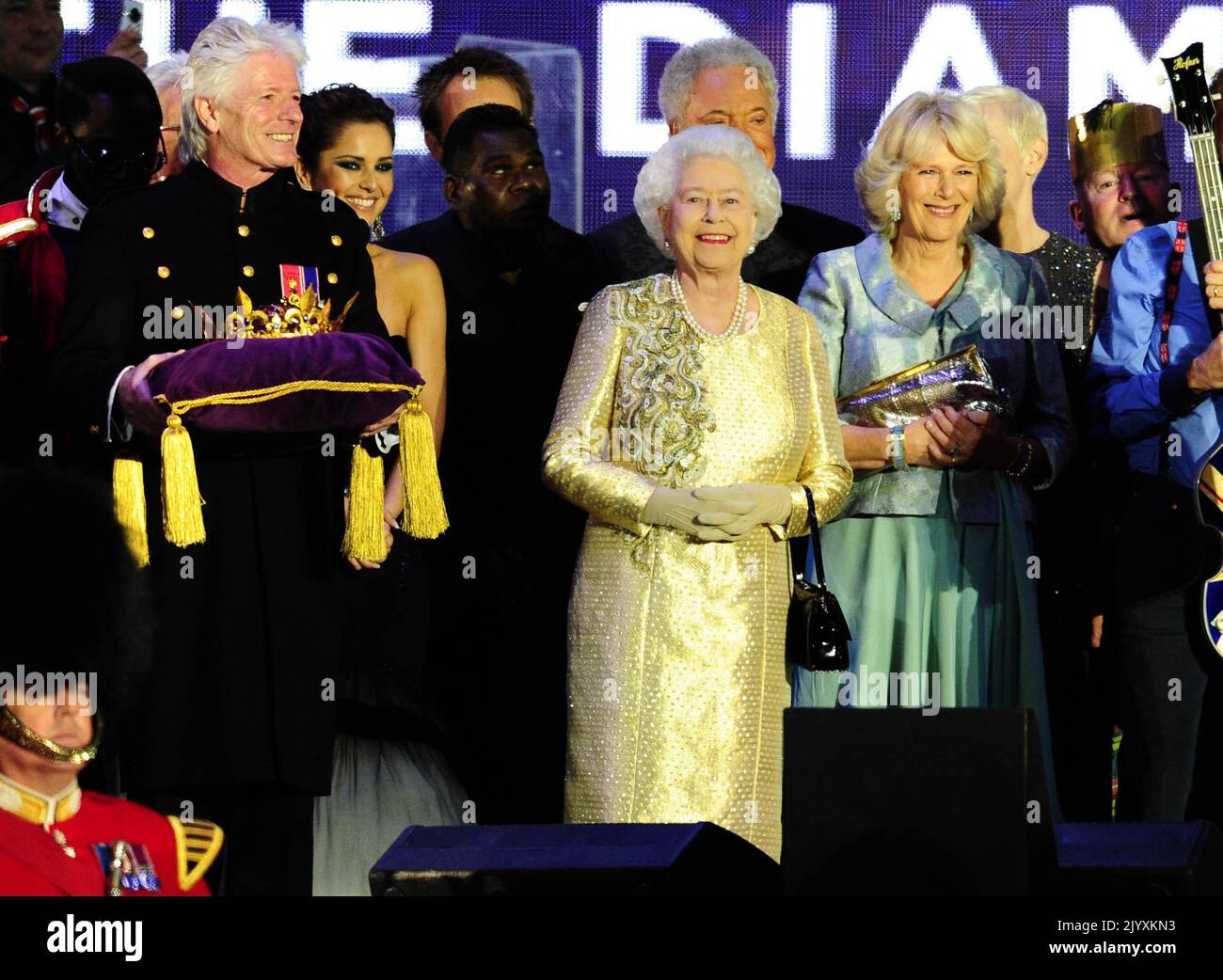 File photo dated 4/6/2012 of Queen Elizabeth II, wearing a gold lame dress by Angela Kelly with trimmings of antique gold and olive lace and Swarovski crystals, on stage outside Buckingham Palace during the Diamond Jubilee Concert. Elizabeth II was famed for her love of block colours and matching hats and her fashion became a legendary part of her role as monarch. The Queen was once described as 'power dressing in extremis' for using vibrant shades to make herself stand out from the crowd while her hats allowed her to be easily spotted but were small enough so her face was visible.Issue date:  Stock Photo