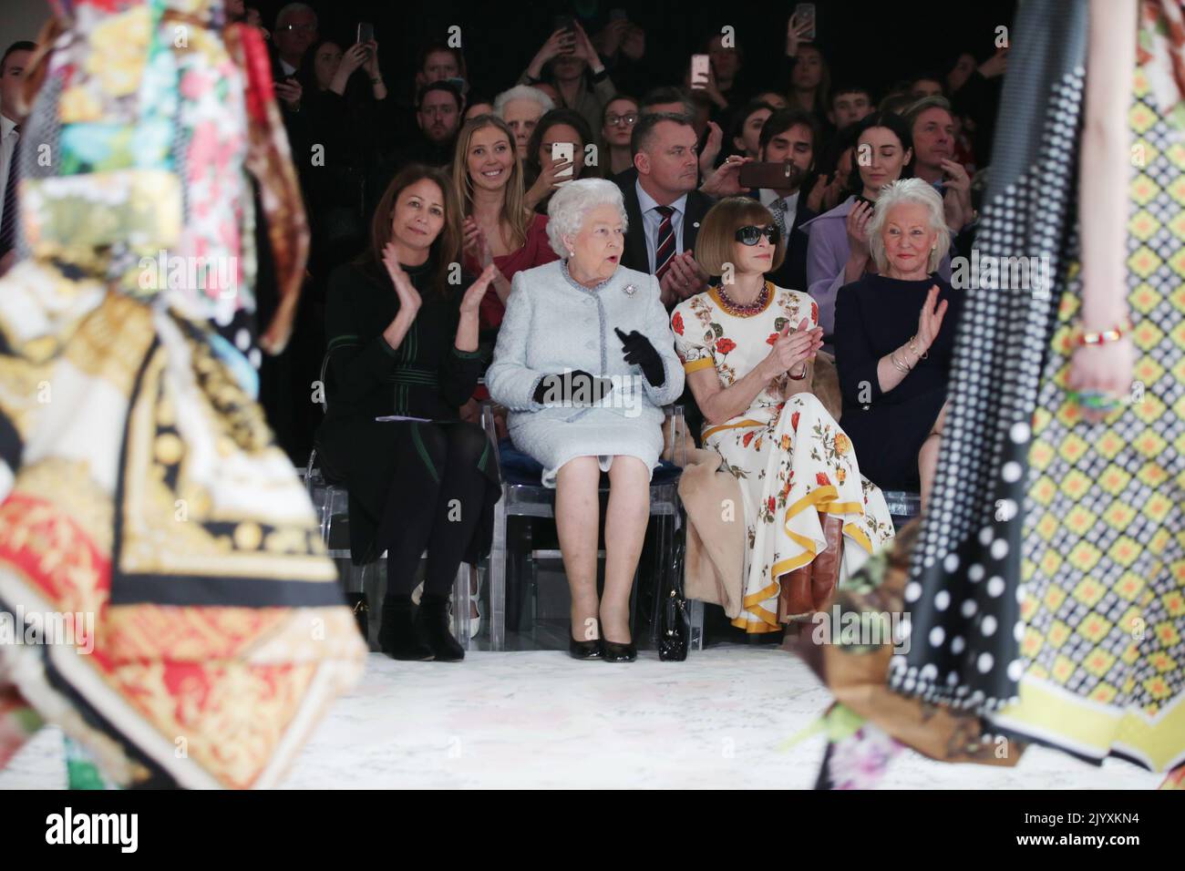 File photo dated 20/2/2018 of Queen Elizabeth II reacts as she sits with Anna Wintour (second right) and Caroline Rush (left), chief executive of the British Fashion Council (BFC) and royal dressmaker Angela Kelly (right), as they watched Richard Quinn's runway show before presenting him with the inaugural Queen Elizabeth II Award for British Design during a visit to London Fashion Week's BFC Show Space in central London. Elizabeth II was famed for her love of block colours and matching hats and her fashion became a legendary part of her role as monarch. The Queen was once described as 'power  Stock Photo