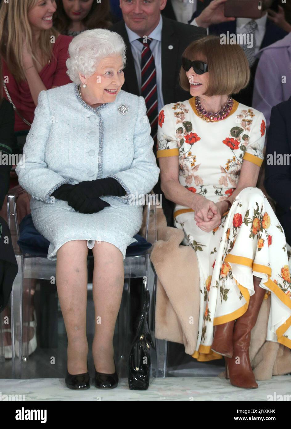 File photo dated 20/2/2018 of Queen Elizabeth II wearing an Angela Kelly tweed dress and jacket in duck egg blue, embellished with tiny aquamarine Swarovski crystals, as she sat next to Anna Wintour (right) as they viewed Richard Quinn's runway show before presenting him with the inaugural Queen Elizabeth II Award for British Design during a visit to London Fashion Week's BFC Show Space in central London. Elizabeth II was famed for her love of block colours and matching hats and her fashion became a legendary part of her role as monarch. The Queen was once described as 'power dressing in extre Stock Photo