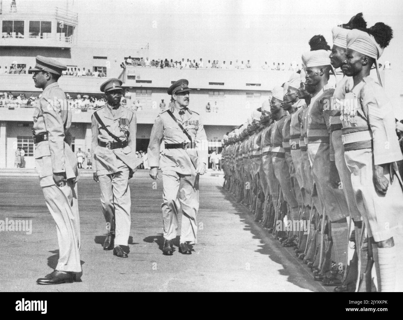 Sudan 'Goodbye' To Departing General -- Before his departure from Khartoum where he has been commanding British Forces Sudan and Commandant of the Sudan Defence Force, Major-General R.L. Scoones, C.B. D.S.O., O.B.E., inspecting the Sudan Defence Force Guard of honour. As part of the process transferring control of the Sudan to the new Sudan Government the post of Commanding Officer of all Sudanese and British troops in the Sudan has been 'Sudanised'. Friends and colleagues who came to Khartoum airport to wish Major-General Scoones goodbye can be seen in the background. He returned to the U. K. Stock Photo