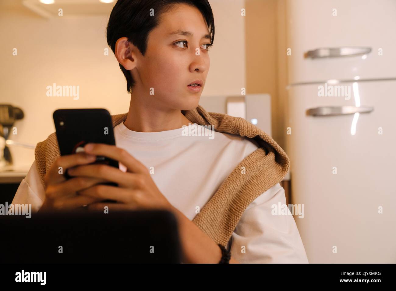 Asian boy using tablet computer and tablet computer in kitchen at home Stock Photo
