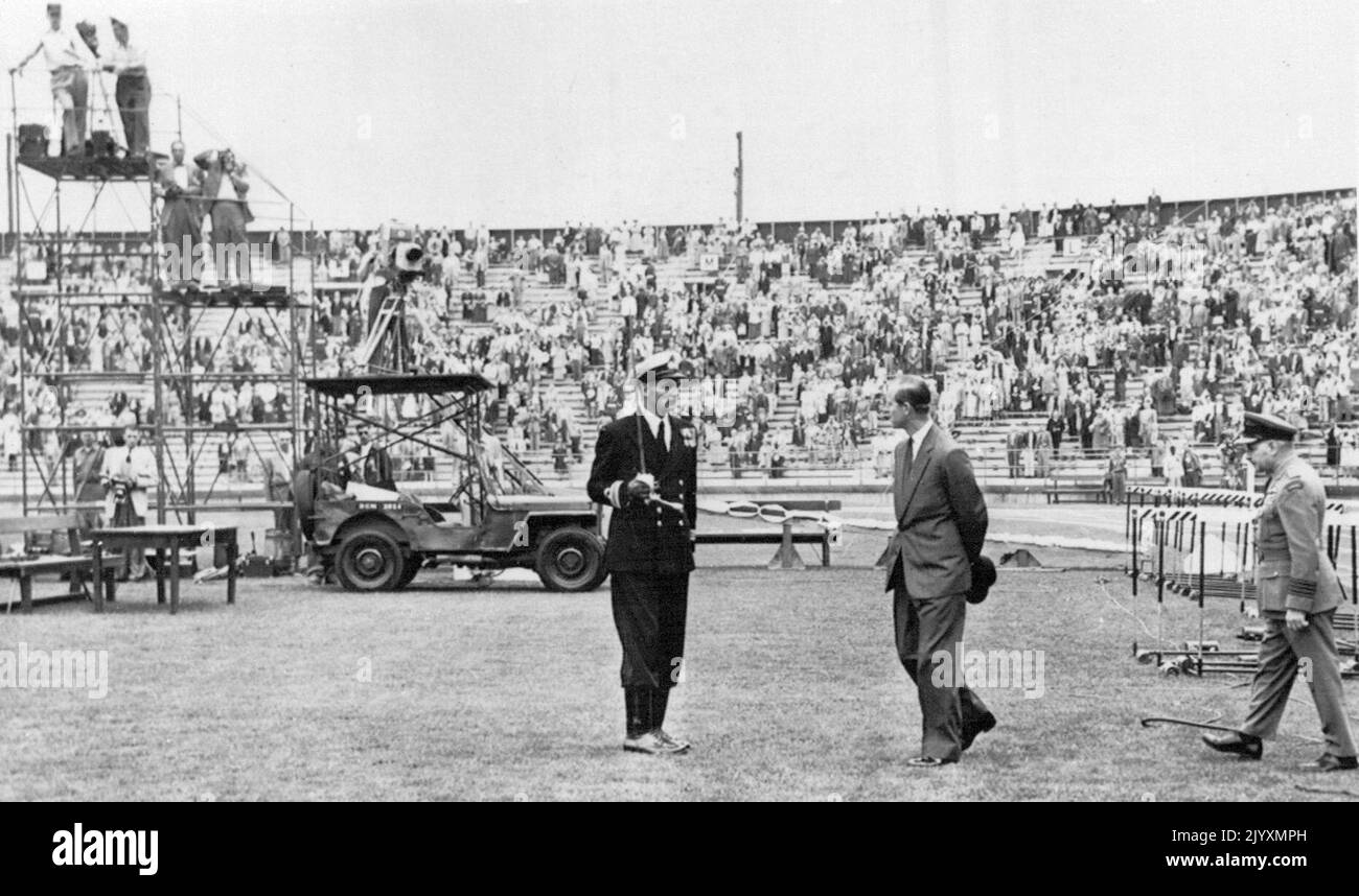 Duke Arrives At Games - The Duke of Edinburgh walks out on field of stadium before many of spectators had arrived at British Empire games today. He is greeted by Lt. Cmdr. A. Piokels, RCN, who. headed a honor guard for duke and at right is RCAF Group Captain Ernest McNab, the Duke's Canadian equerry. August 05, 1954. (Photo by AP Wirephoto) Stock Photo