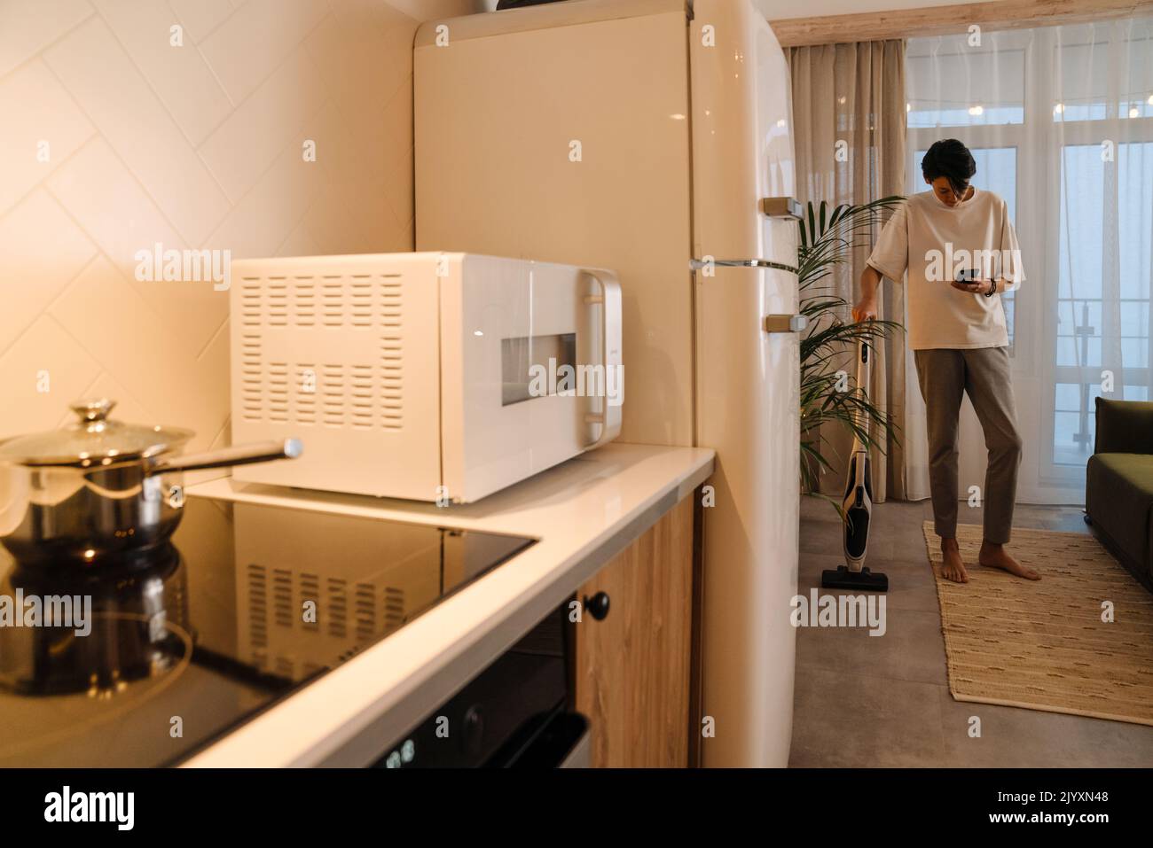 Asian boy using mobile phone while doing housework at home Stock Photo
