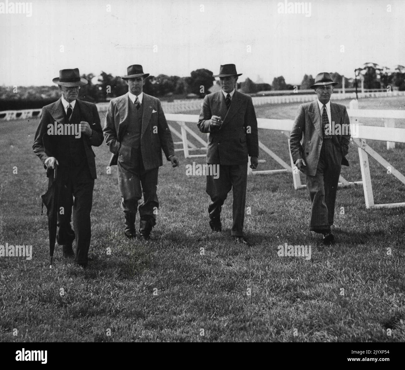 Race Track Inspection -- The track at Flemington racecourse being inspected today after yesterday's heavy downpour. Above (from left): Mr. D. W. Reid (stipendiary steward), the secretary of the Melbourne Racing Club (Mr. John C. Reilly), Mr. N. W. Faulkiner (stipendiary steward), and the racecourse supervisor (Mr. W. Mitchell). November 16, 1949. Stock Photo