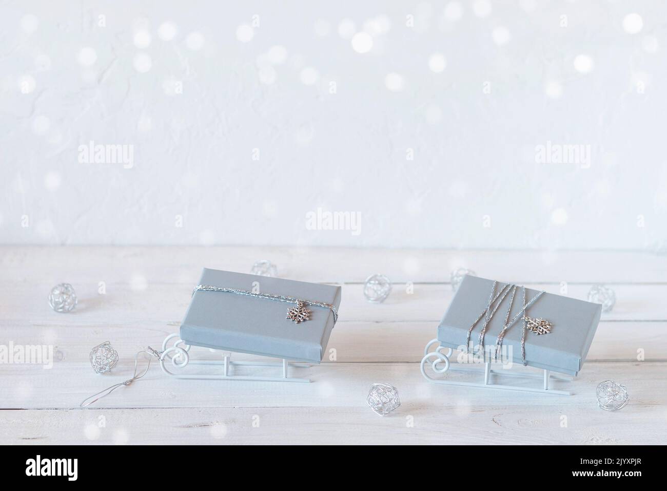 tiny decorative sleds with grey Christmas gift boxes, white, grey and silver colors, copy space, idea for Christmas card Stock Photo