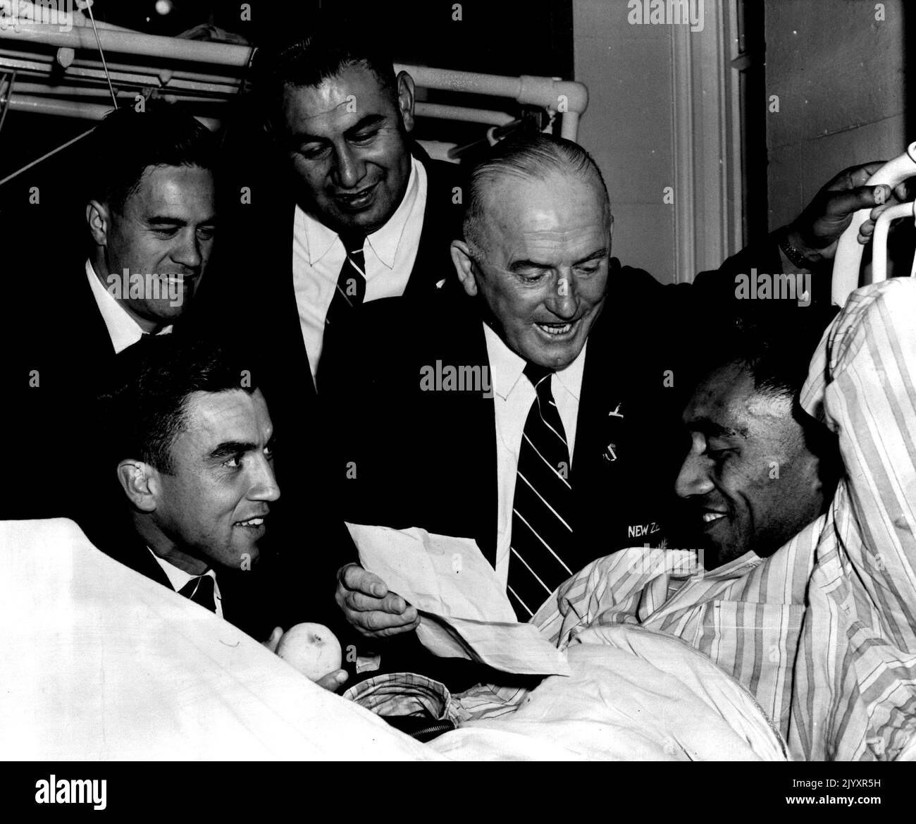 The New Zealand Prime Minister, Mr. W. Nash, yesterday sent a cable to Maori Rugby Union centre Bill Gray, who broke a leg in Saturday's match against Sounth Harbour. The cable wished Gray a speedy recovery. Team manager Mr. Frank Kilby and teammates R. Keepa, P. Walsh and R. Byers (sitting) took the message to Gray in hospital. June 3, 1953. (Photo by Australian Photographic Agency). Stock Photo
