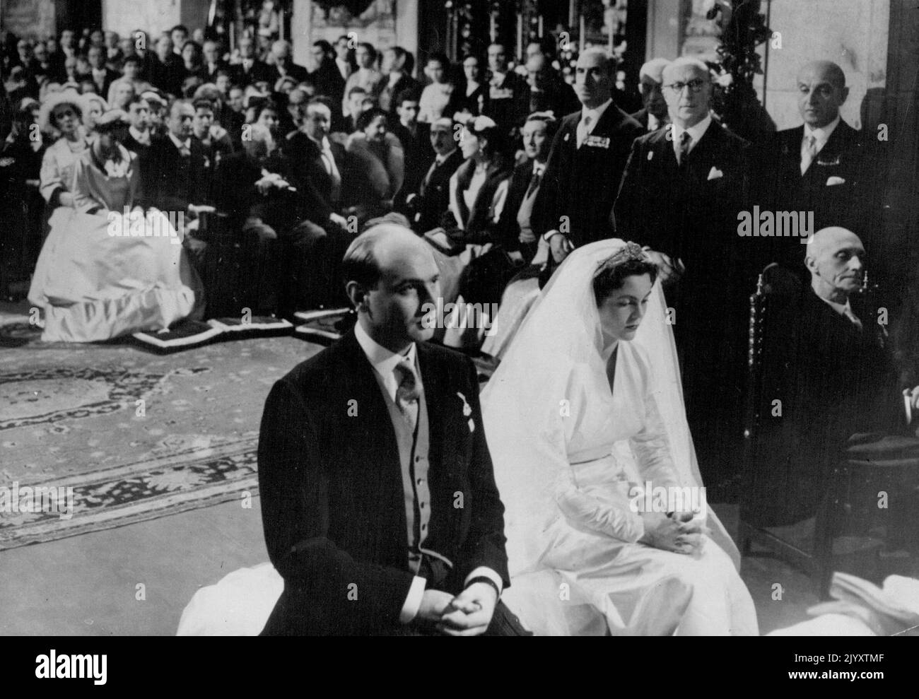 The Royal Wedding Photo Shows: Princes Maria Pia of Savoy and Prince Alexander seated in front of the alter during the wedding ceremony. The duchess of Kent (England) is seen in read (second row with leaning outwards wearing large *****) with her children the duke of Kent and Princess Alexandra beside her. The Royal Wedding - Princess Maria Pia of Italy married Prince Alexander of Yugoslavia in the small while Church at Casais. A Tiny Fishing village 20 miles from Lisbon Portugal., February 12. Among the large number of Royal guests at the ceremony were six ex-Kings. These had favored places i Stock Photo