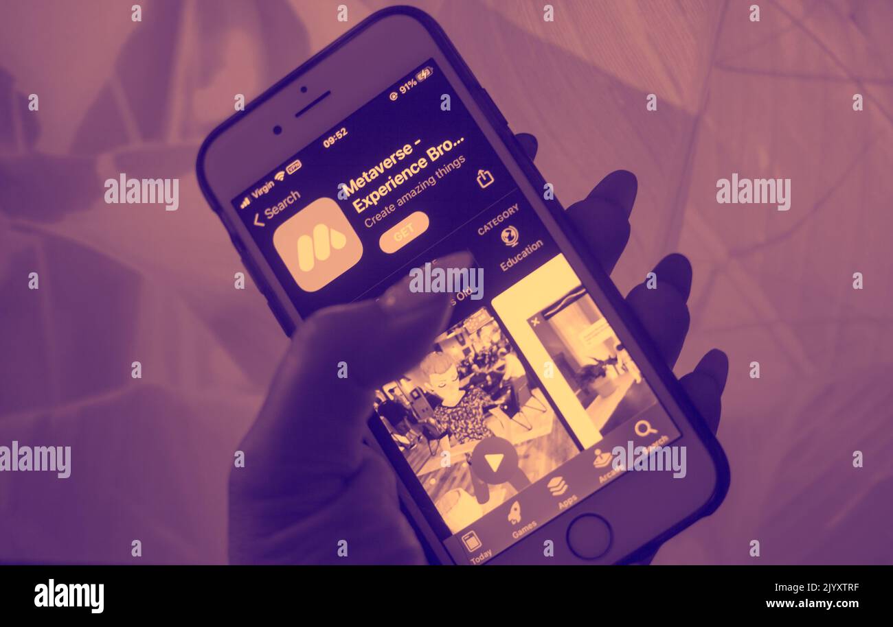 Metaverse Tech Lifestyle Concept - Close-up of a hand holding a mobile phone with metaverse experience app on screen display. Stock Photo