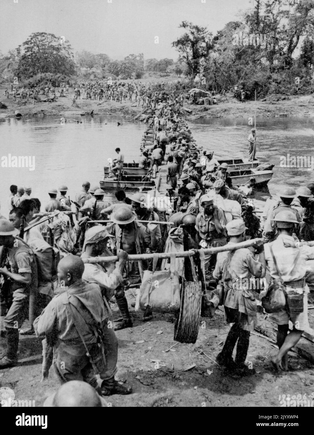 Yanks And Chinese On March In Burma -- American And Chinese troops cross an improvised bridge constructed of planks over empty gasoline cans lashed together, as they proceed over the Mogaung river on their way to Kamaing, Burma. March 08, 1944. (Photo by Associated Press Photo) Stock Photo
