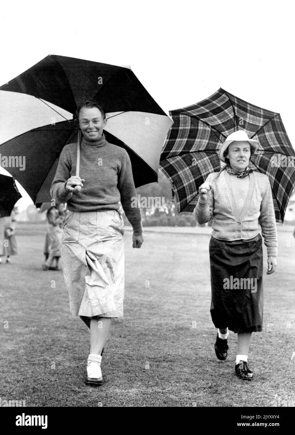 Wet weather married the second day's play in the Australian women’s Jubilee amateur golf championships at Kooyonga on Thursday. Here Miss J. Percy (Q), left, and Miss B. Kernot (Vic.) walk to the 17th green. Both were in the 16 to qualify, and Miss Percy’s 77 was the best round for the day. September 1, 1951. Stock Photo