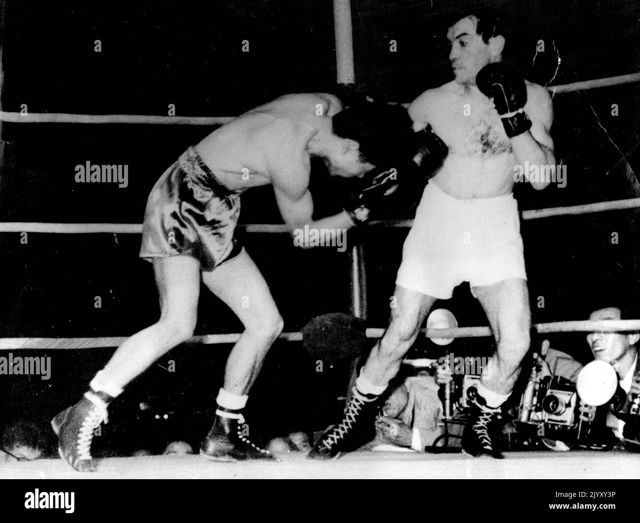 Japanese Yoshio Shirai (left) about to fall to the canvas as Argentinian Parcual Perez connects with a stiff right in the fifth round of their world flyweight title fight at Tokio. Shirai was counted out. June 13, 1955. Stock Photo