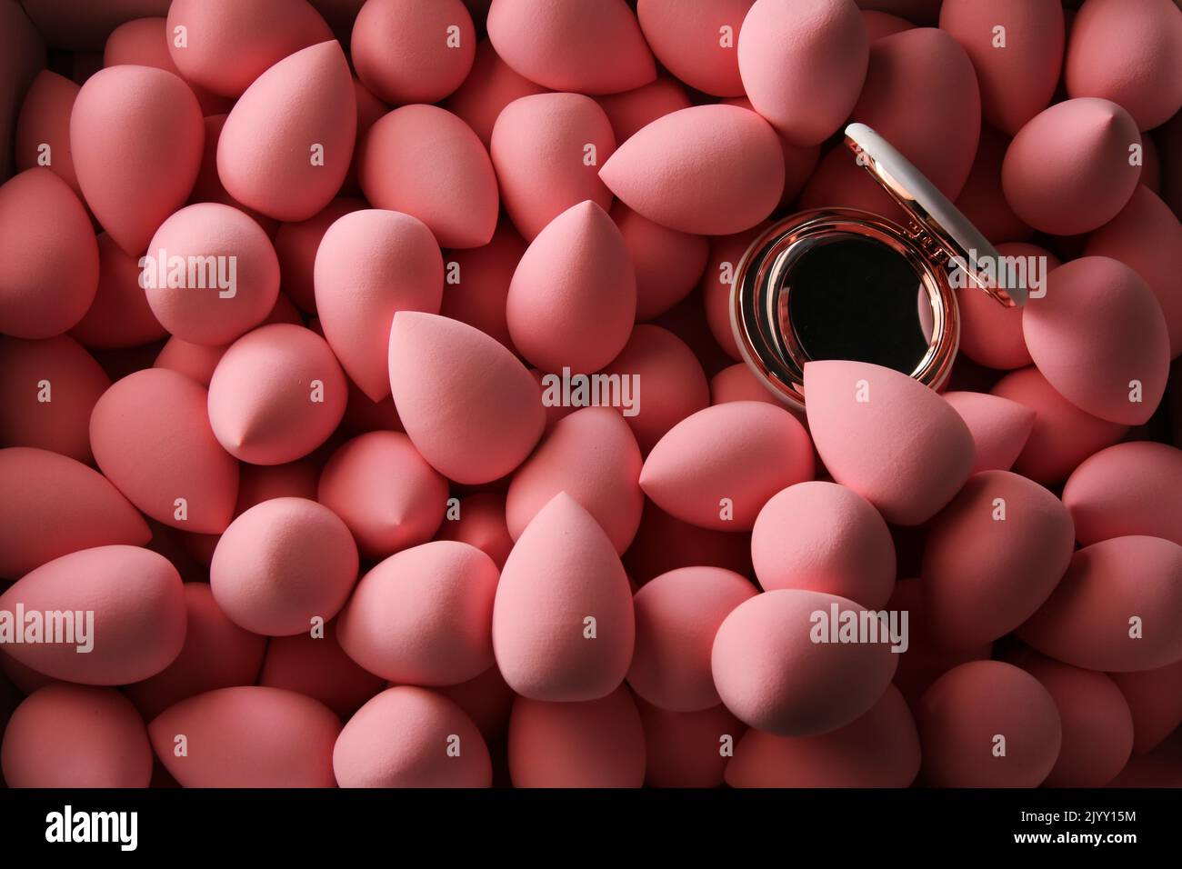beauty background a bunch of pink gentle makeup sponges and a mirror dark key Stock Photo