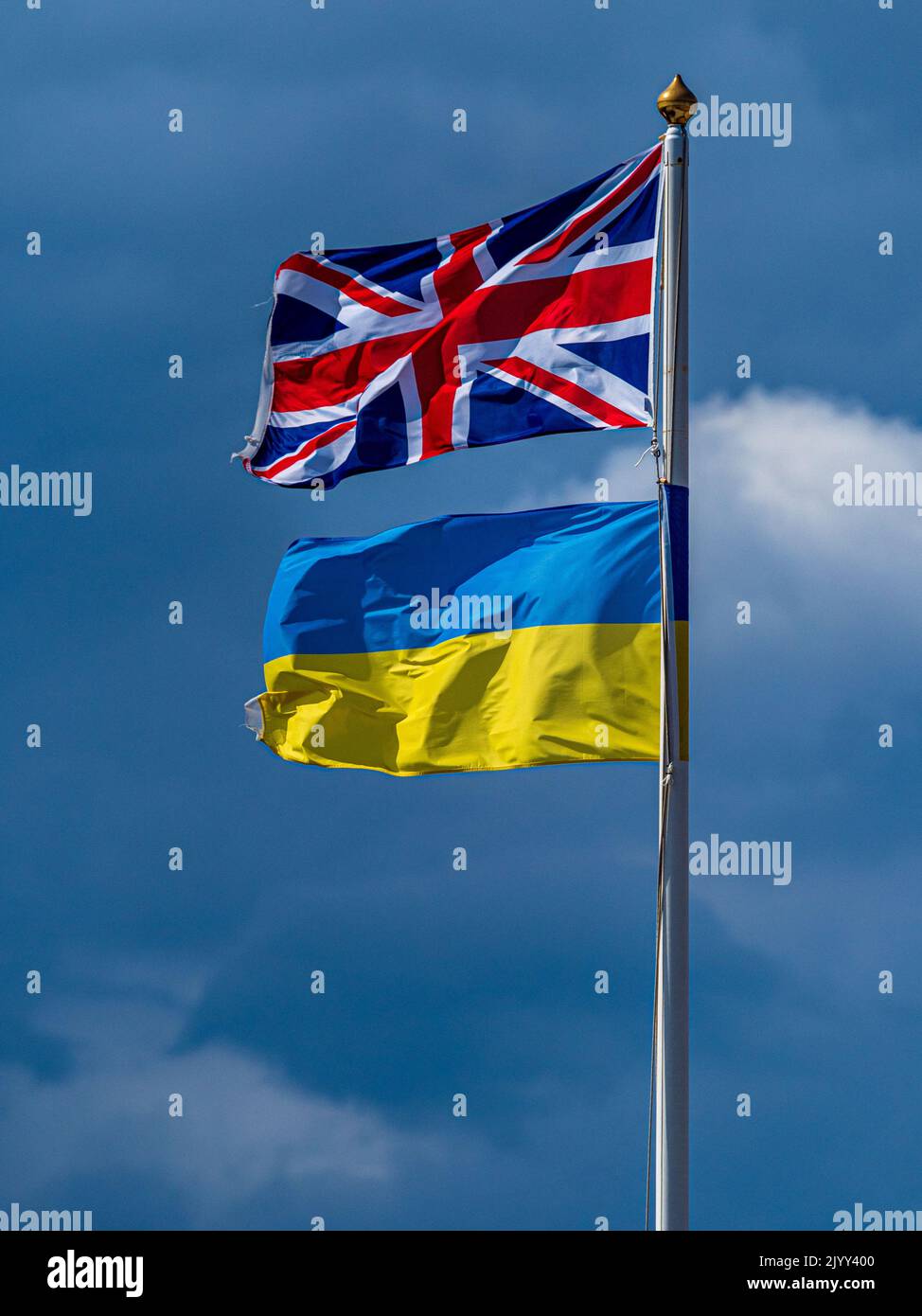 UK and Ukraine flags fly together in a display of solidarity. British and Ukrainian Flags.  British and Ukraine flag display. Stock Photo