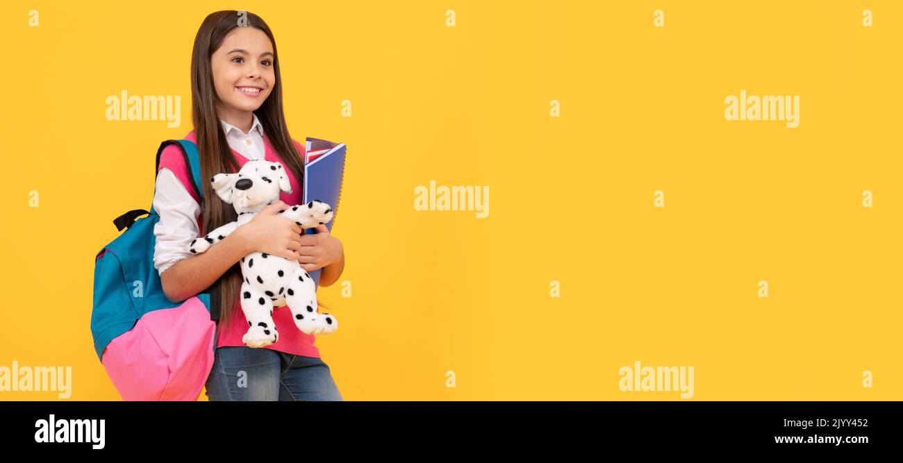 happy teen school girl with backpack and copybook hold toy on yellow ...