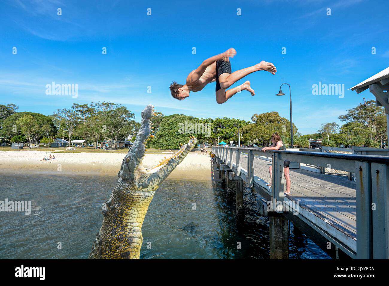 Young boy jumping from the jetty at popular Bongaree Beach, Bribie Island, Sunshine Coast, Queensland, QLD, Australia Stock Photo