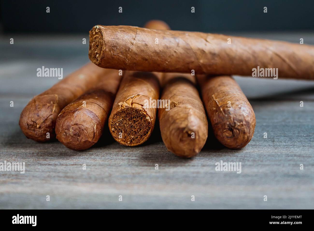 Cuban cigars on rustic wooden table in line on the edge of background. Stock Photo