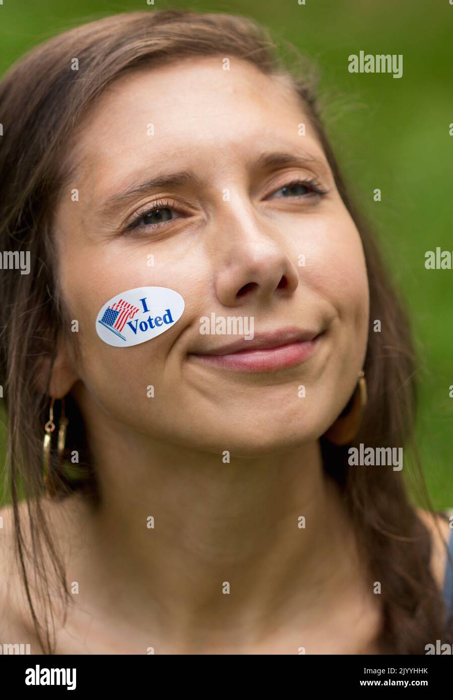 A young woman has a sticker on her face that reads 'I voted.' Stock Photo
