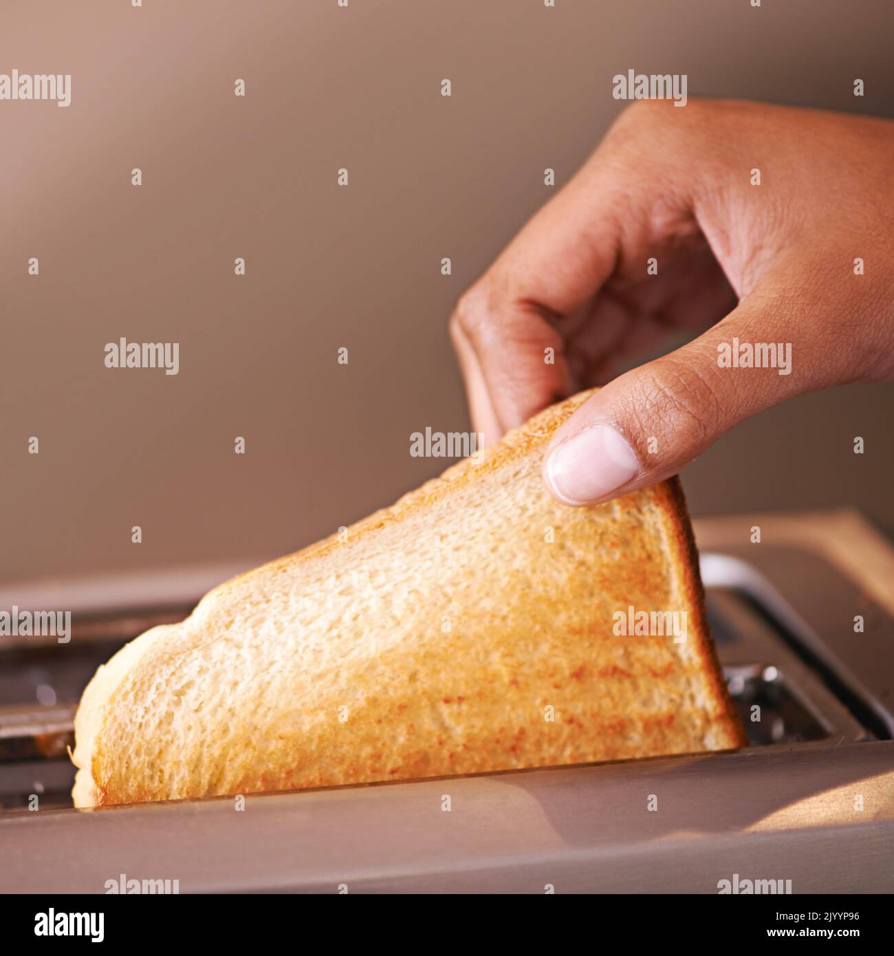 Toasty tastiness. a woman taking toast out of a toaster Stock Photo Alamy