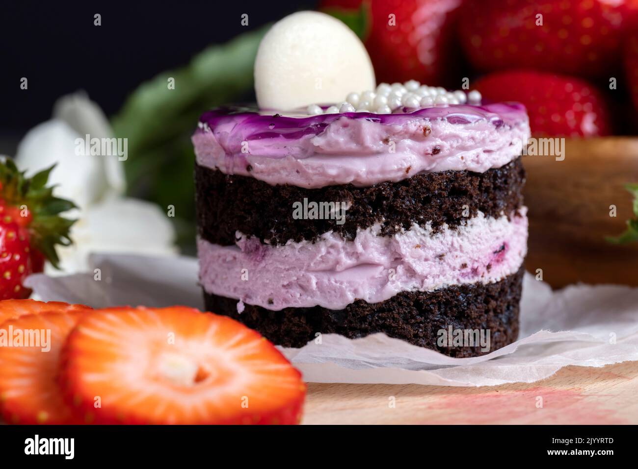 purple cake with berry flavor, sweet dessert cake with red strawberries Stock Photo