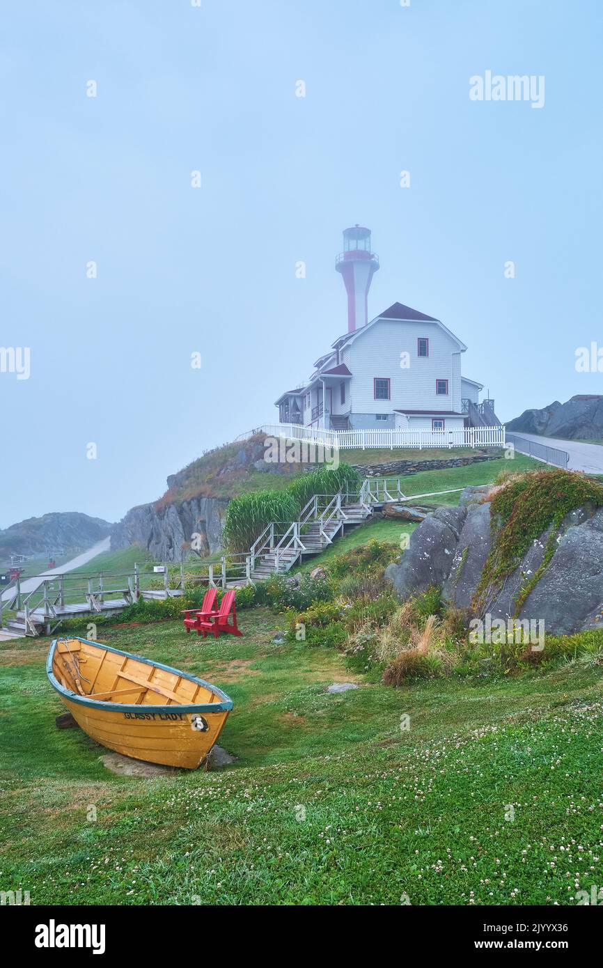 The lighthouse on Cape Forchu Nova Scotia on a misty morning with a bright yellow dory in the foreground. Stock Photo