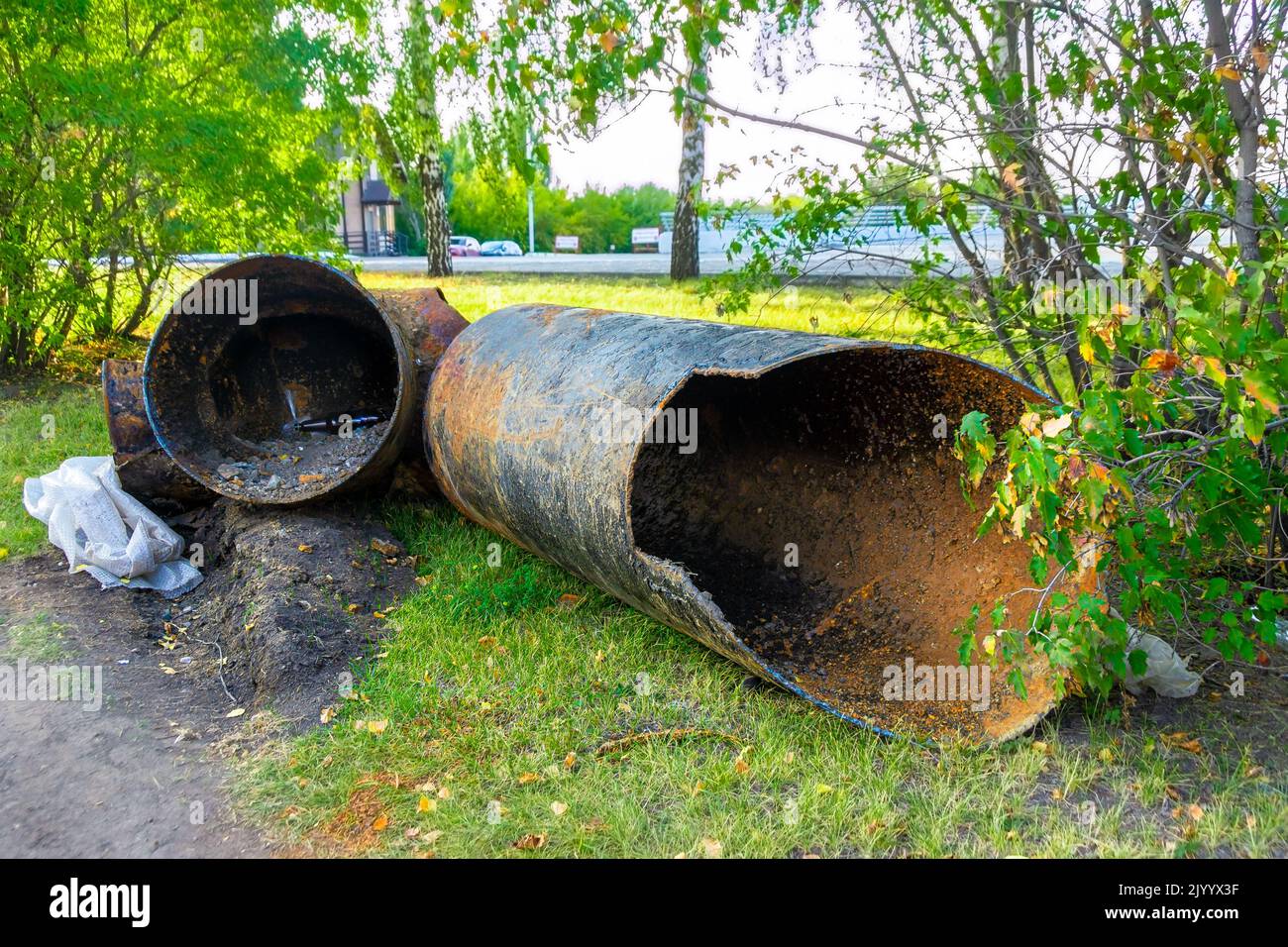 a piece of an old pipe cut out during the repair work of the pipeline lies on the grass in anticipation of removal and subsequent disposal, selective Stock Photo