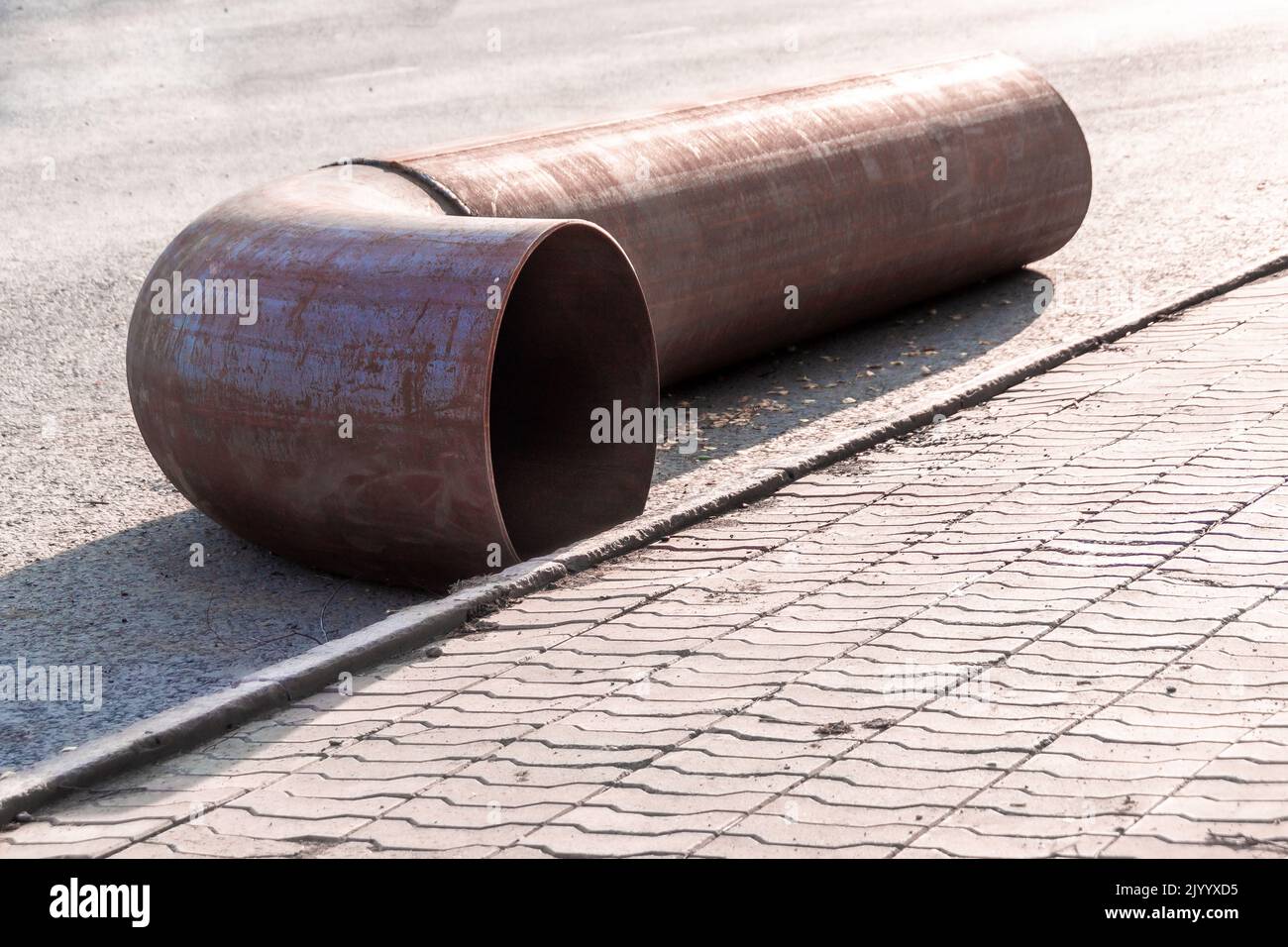 a new fitting pipe turn lies on the pavement waiting for the repair of the main pipe, backlight and selective focus Stock Photo