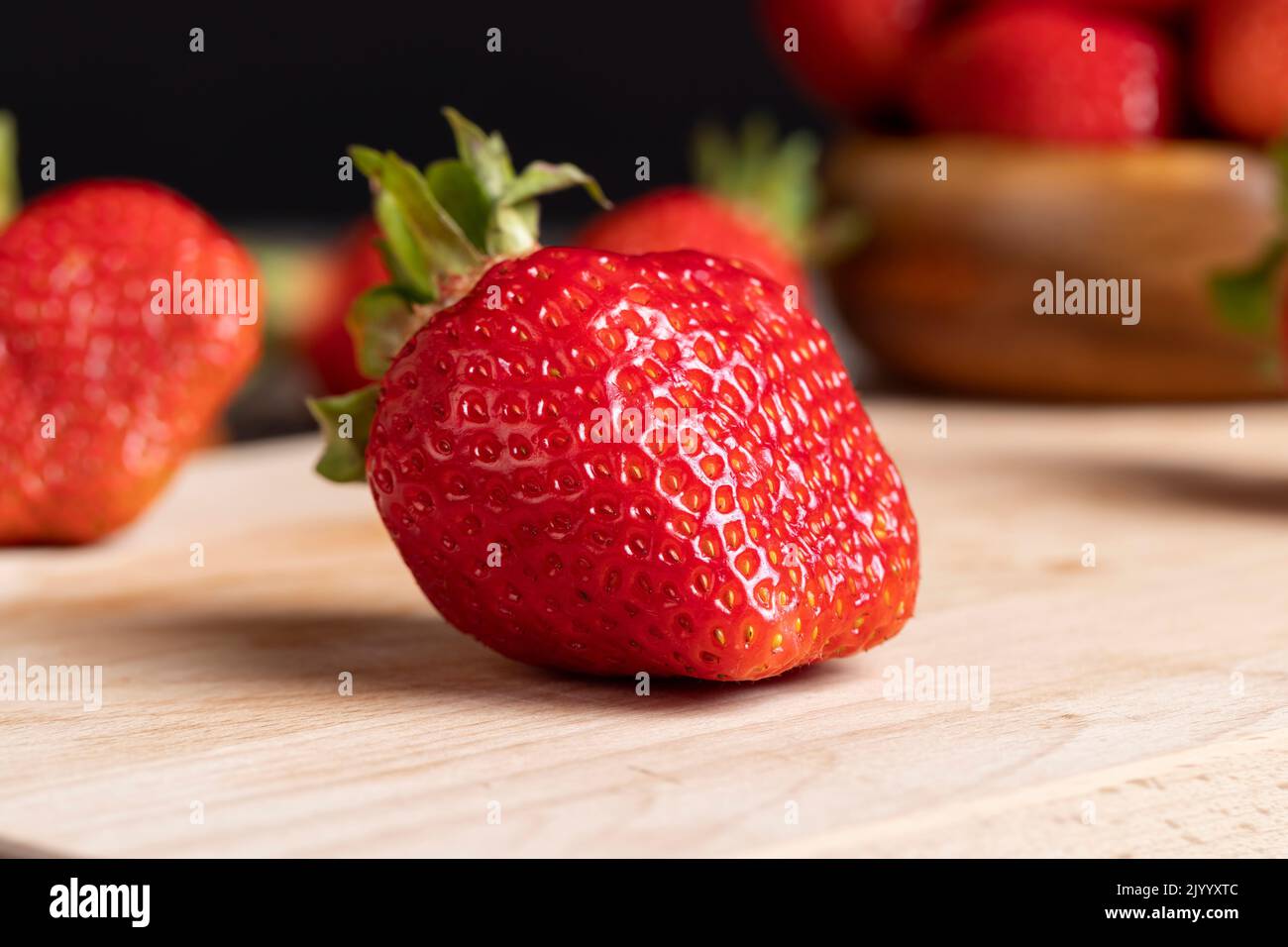 Ripe red strawberries lying on a wooden tray, red strawberries during cooking Stock Photo