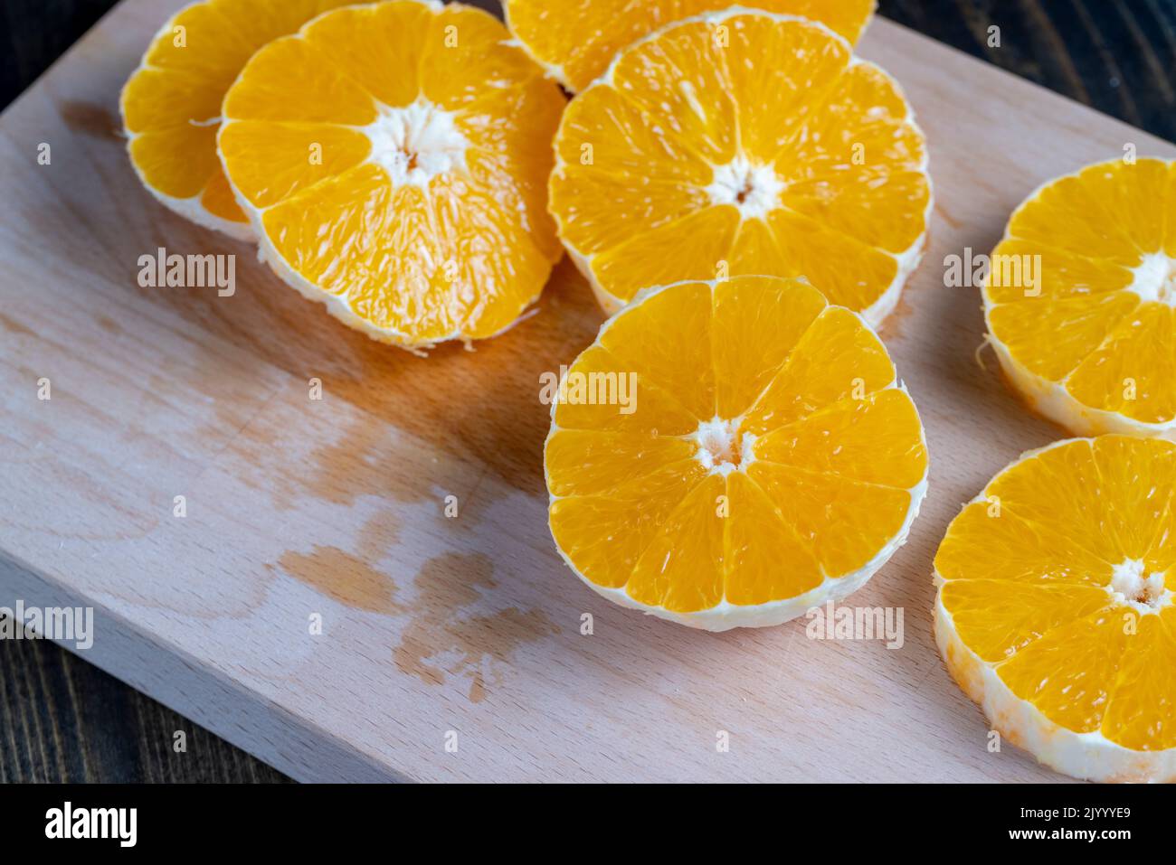 peeled ripe orange cut into slices during cooking, ripe orange divided into pieces with a knife Stock Photo