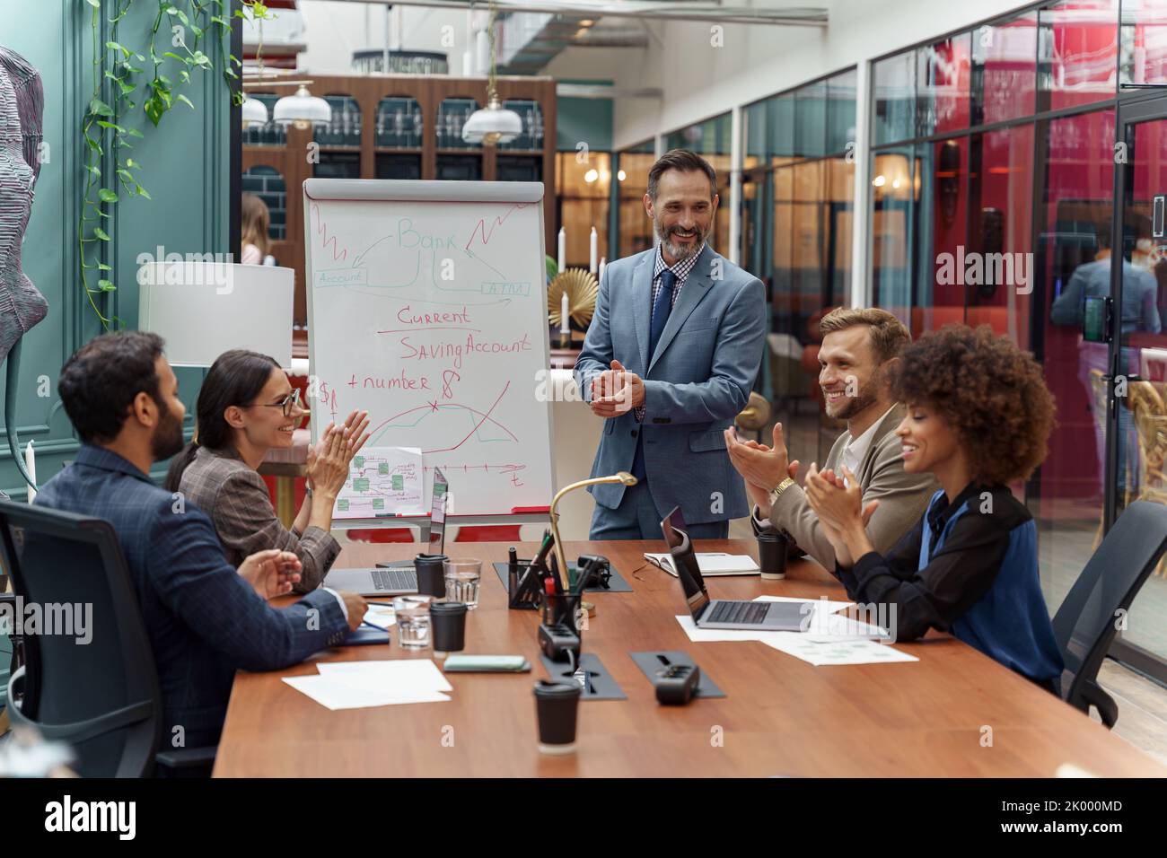 Mature business coach or speaker make flip chart presentation to diverse businesspeople at meeting Stock Photo