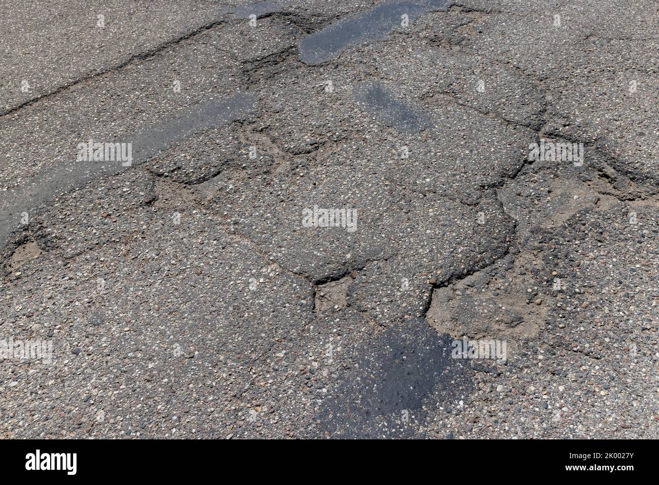 An old paved road with a lot of holes and damage, very poor quality of the highway with damaged non-quality asphalt Stock Photo
