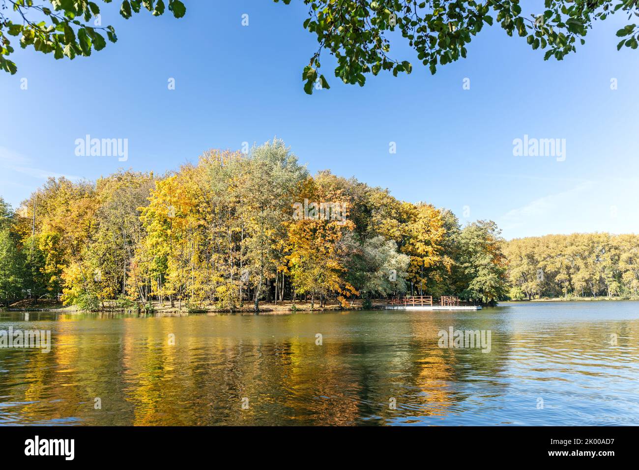 bright autumn trees under clear blue sky are reflected in the water of lake Stock Photo