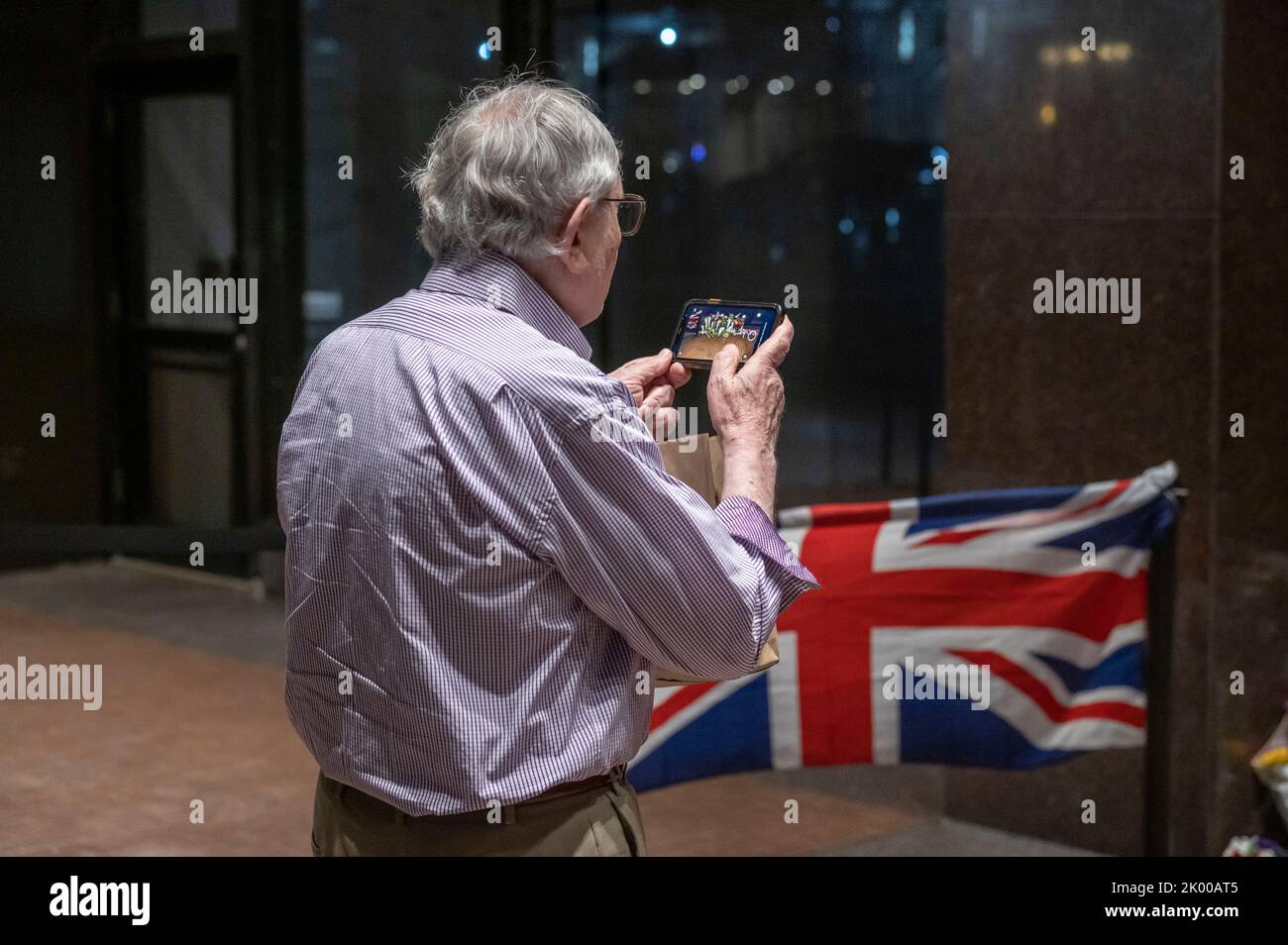 New York, United States. 08th Sep, 2022. A member of the public records on his phone the memorial for Her Majesty Queen Elizabeth II outside The British Consulate General in New York. According to a statement issued by Buckingham Palace on 08 September 2022, Britain's Queen Elizabeth II has died at her Scottish estate, Balmoral Castle. The 96-year-old Queen was the longest-reigning monarch in British history. Credit: SOPA Images Limited/Alamy Live News Stock Photo