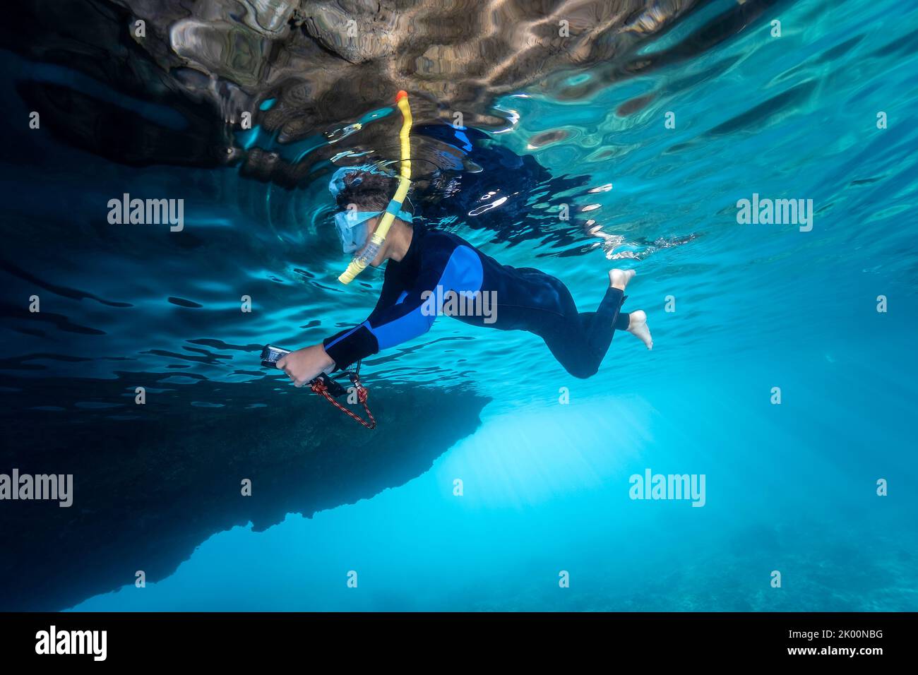 Little boy with a neoprene suit snorkeling with an action camera in a Mediterranean cave Stock Photo