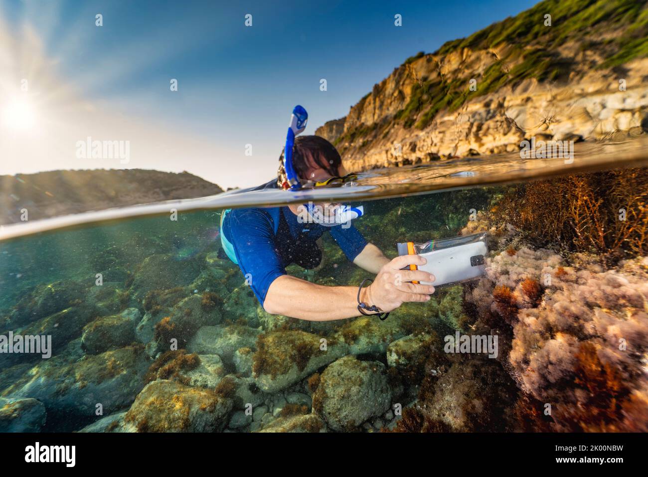 Snorkeller taking pictures underwater with a cellular phone in a waterproof bag Stock Photo