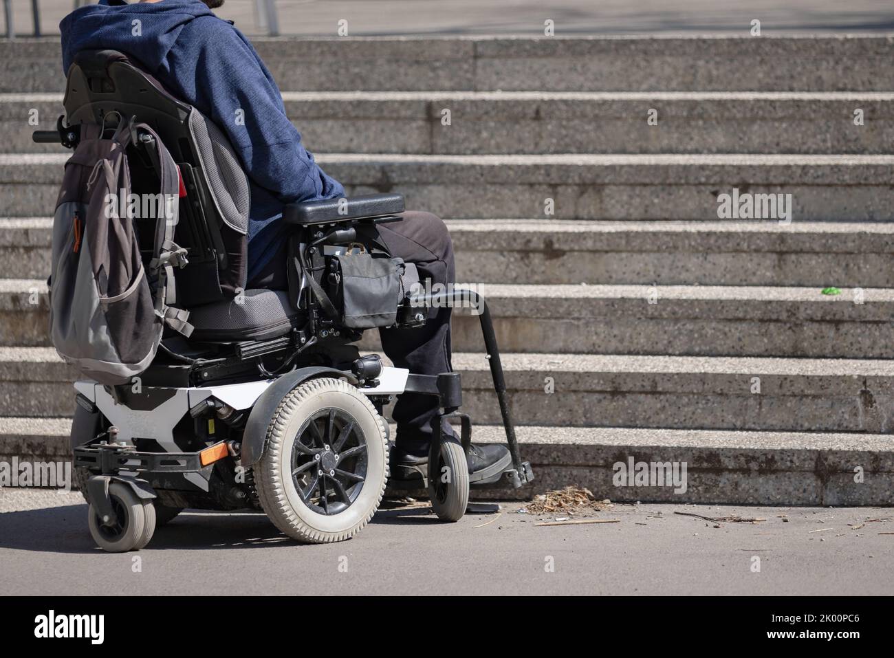 Man with disability on wheelchair stopped in front of staircase