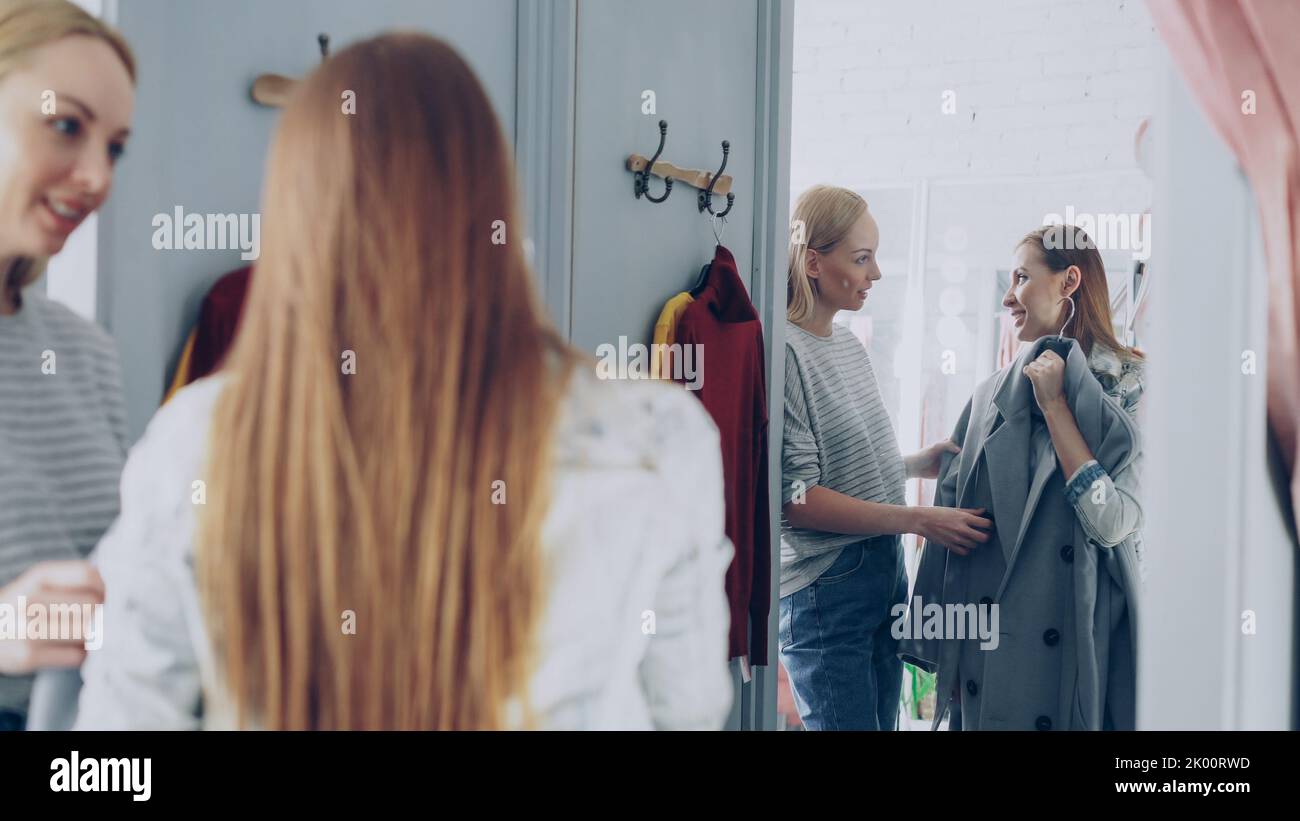 Pretty young woman is checking fashionable coat in fitting room with