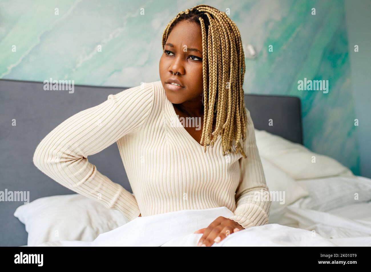 latin american woman suffering from back ache on the bed after sleeping