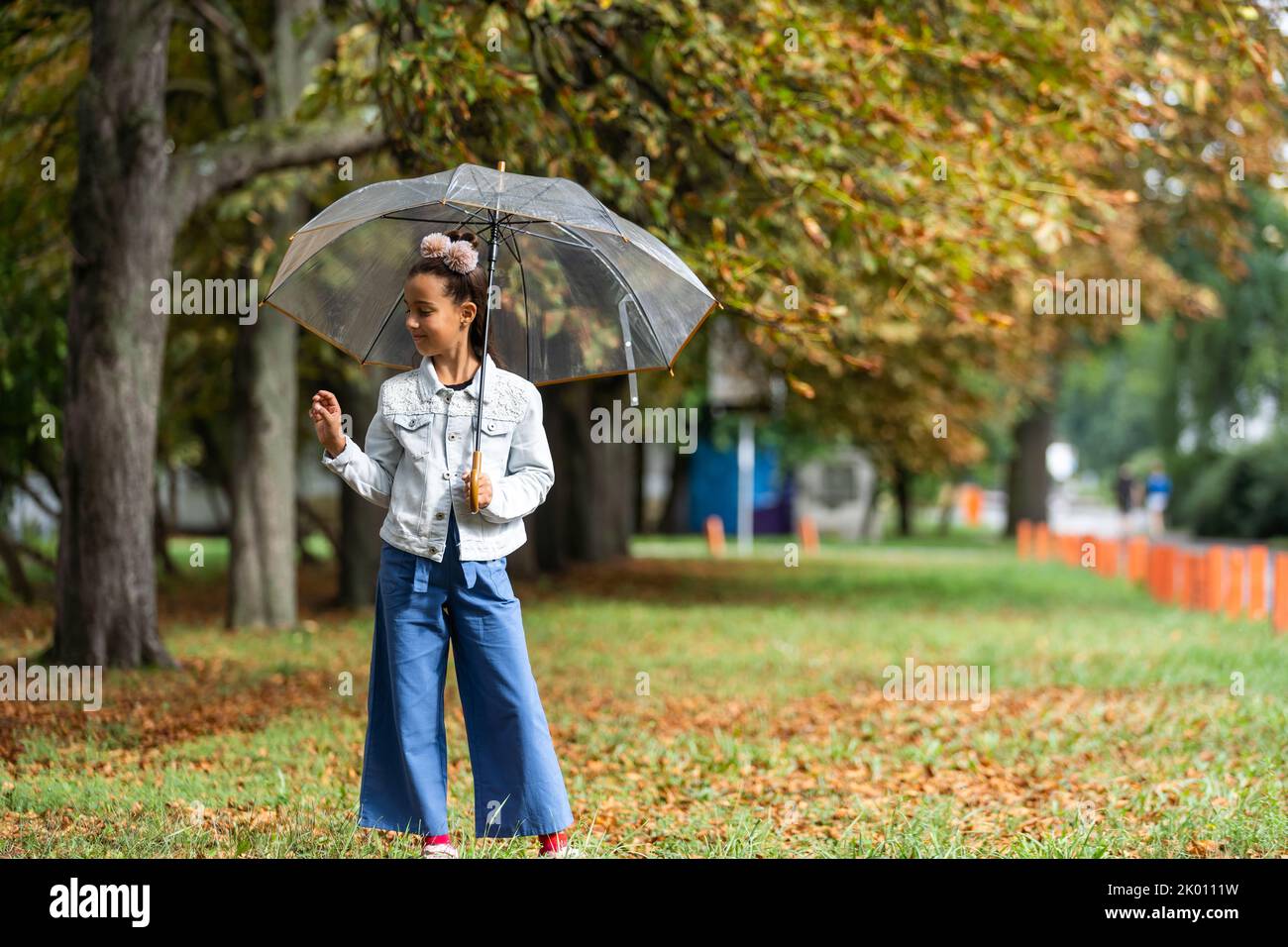 Kid playing out in the rain. Children with umbrella play outdoors in