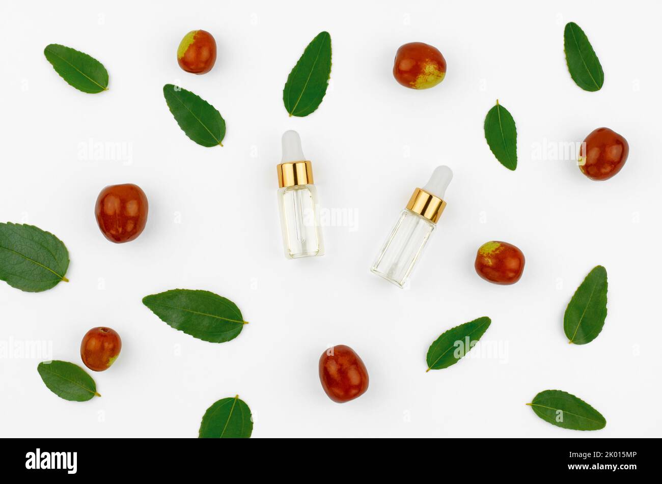 Chinese date fruit and oil. Jojoba oil in a transparent bottle with a dropper and fresh jojoba fruit on a white background Stock Photo
